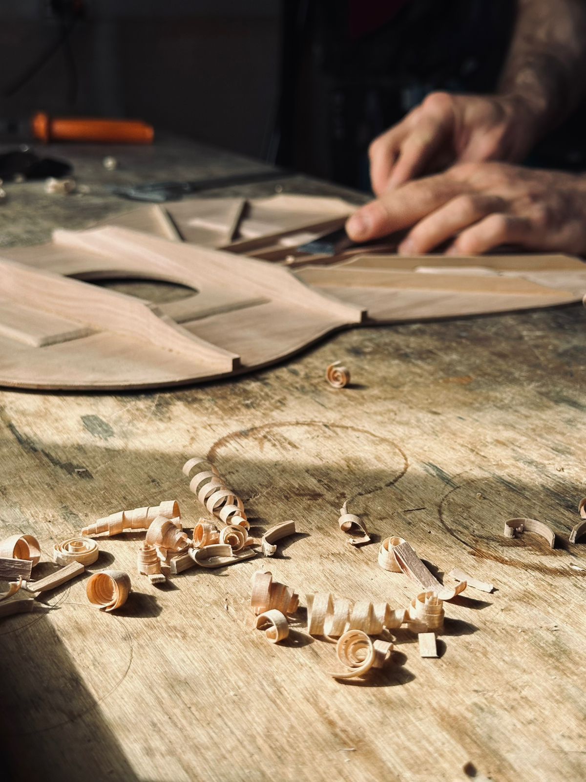 Manos trabajando una tapa de guitarra en el taller